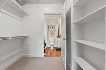 A white hallway with a toilet and a door.
